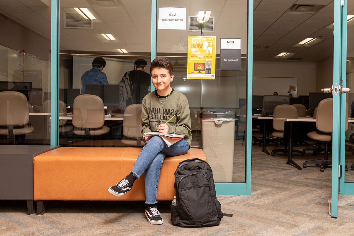 SJC student sitting on a bench outside of a classroom studying